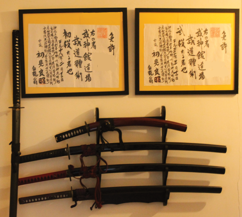 five Sword on wall with framed certificates above them